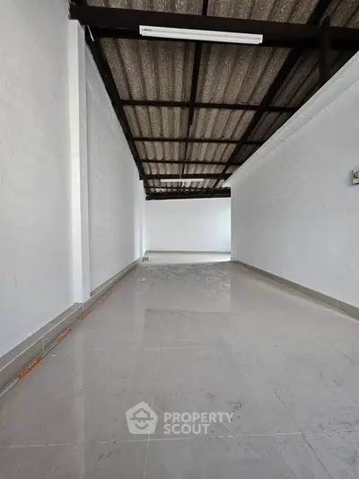 Spacious covered area with tiled flooring and corrugated roof, ideal for storage or utility use.