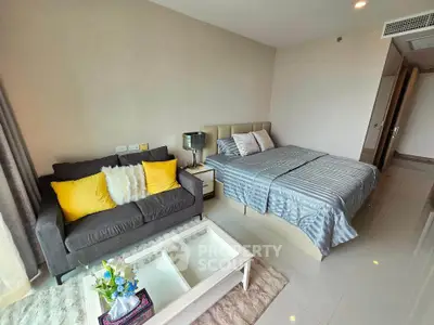 Modern bedroom with cozy seating area and stylish decor, featuring a plush bed and vibrant cushions.