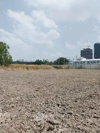 Expansive vacant land with city skyline backdrop, ideal for development opportunities.