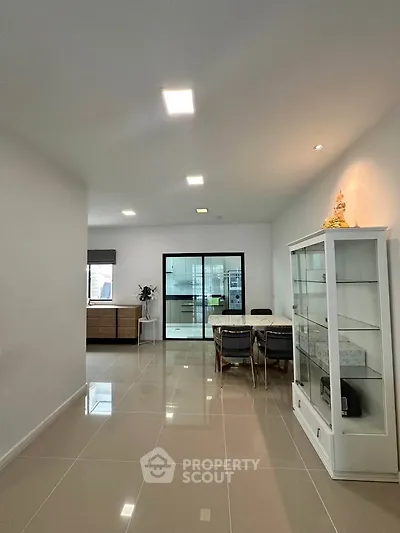 Spacious modern dining area with sleek glass cabinet and elegant lighting