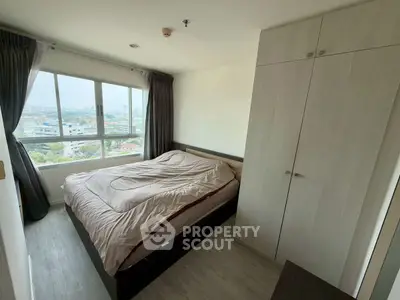 Cozy bedroom with large window offering stunning city views and ample natural light.