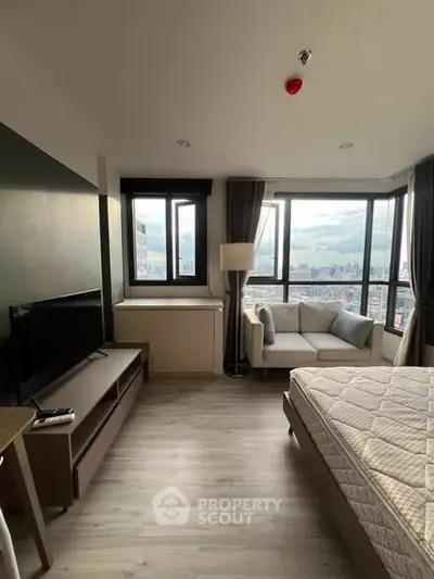 Modern bedroom with city view, featuring a cozy sofa and sleek TV stand, perfect for urban living.