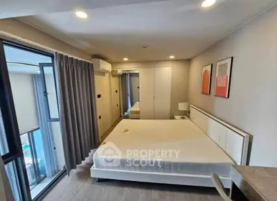 Modern bedroom with large window and stylish decor in a contemporary apartment.