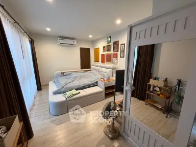 Spacious bedroom with modern decor and natural light, featuring a cozy bed and stylish furnishings.