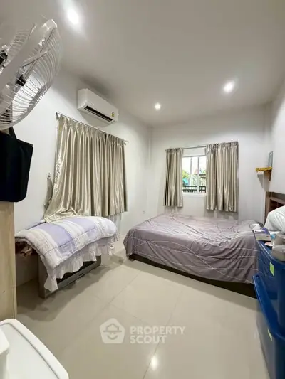 Cozy bedroom with air conditioning and natural light, featuring modern furnishings and neutral decor.