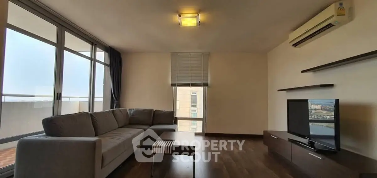 Spacious living room with modern sofa and large windows offering natural light.
