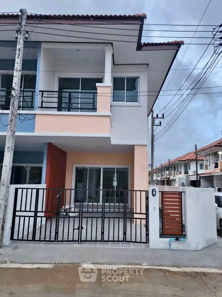 Modern two-story townhouse with gated entrance and spacious balcony in a suburban neighborhood.