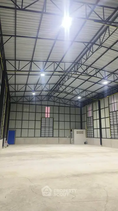 Spacious industrial warehouse with high ceilings and ample lighting, perfect for storage or manufacturing needs.