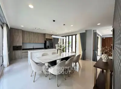 Spacious modern kitchen with open layout and elegant dining area, featuring sleek cabinetry and large windows.