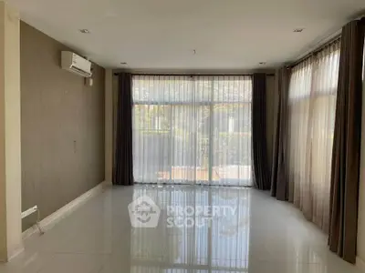 Spacious living room with large windows and elegant curtains, perfect for natural light and modern living.