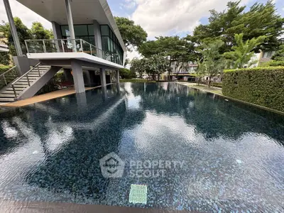 Luxurious modern poolside view with lush greenery and contemporary architecture.