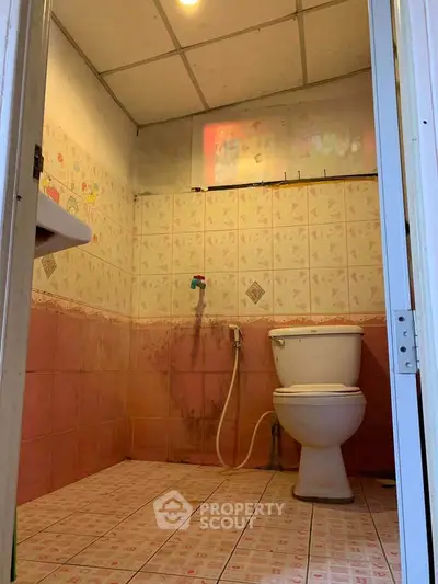 Cozy bathroom with pink tiles and modern toilet in a compact space.