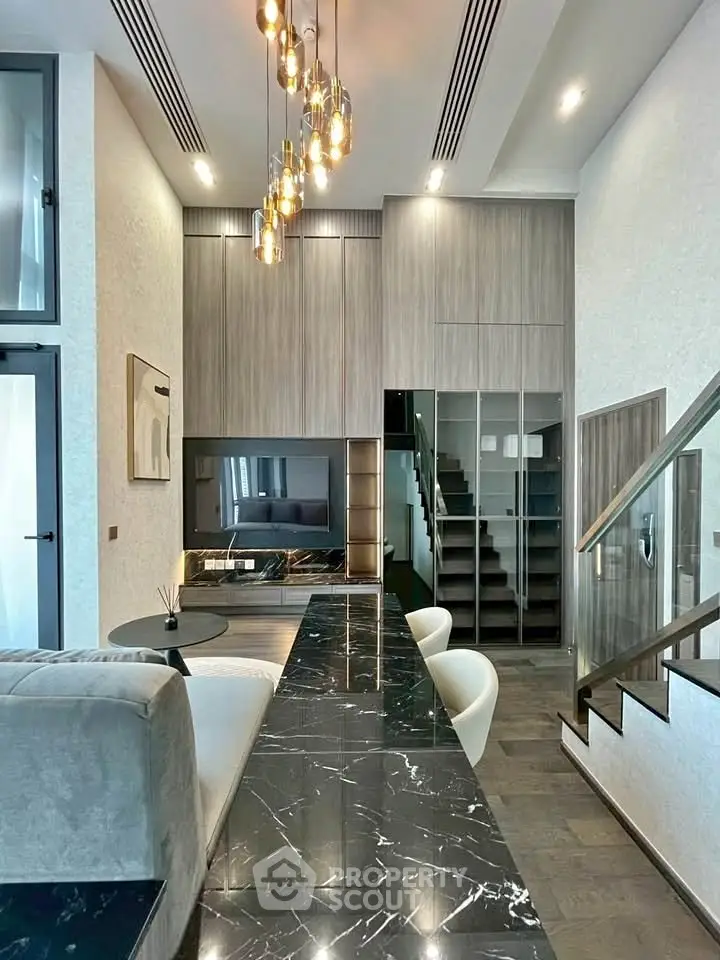 Luxurious modern living room with high ceilings, elegant lighting, and stylish staircase