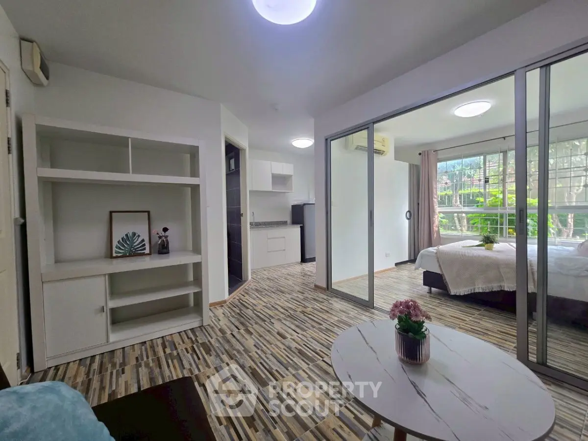 Modern open-plan living room with sliding doors to bedroom, featuring stylish flooring and natural light.
