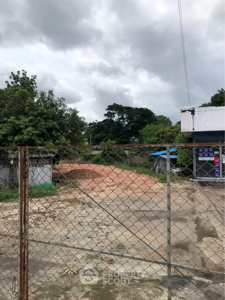 Vacant land with potential for development, surrounded by greenery and a clear sky.