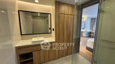 Modern bathroom with wooden cabinetry and glass shower in a stylish apartment.