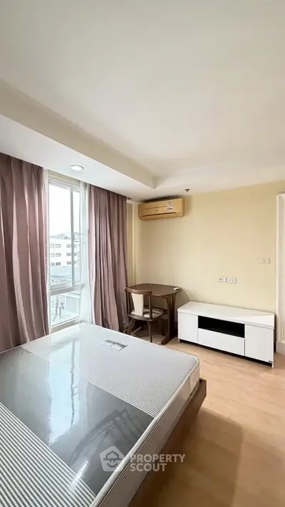 Bright bedroom with large window, air conditioning, and modern furniture in a stylish apartment.