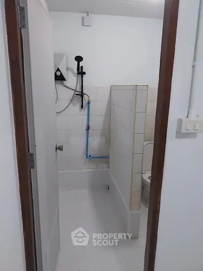 Compact bathroom with tiled walls and modern fixtures, ideal for efficient space utilization.