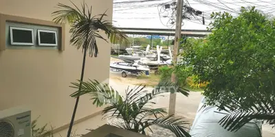 Charming exterior view with lush greenery and nearby boat storage area.
