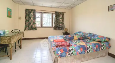 Spacious bedroom with colorful bedding and natural light from window.