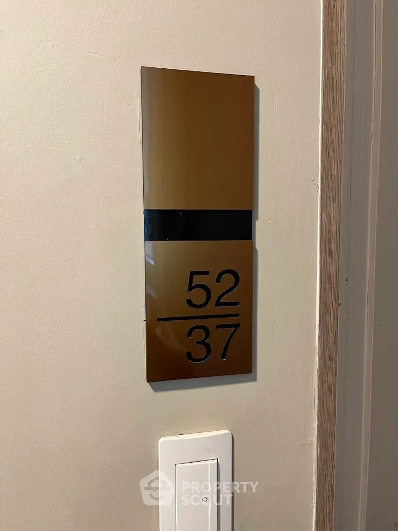Modern apartment door number sign with sleek design and neutral tones.