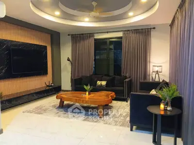 Luxurious living room with modern decor, large TV, and elegant lighting