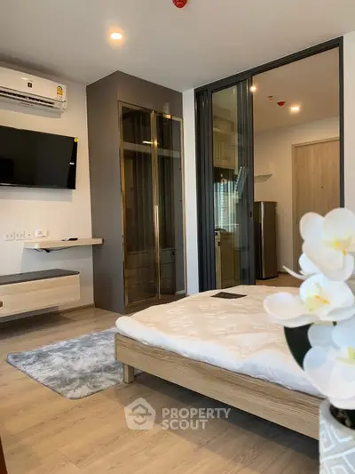 Modern bedroom with sleek design, featuring a wall-mounted TV, air conditioning, and elegant decor.