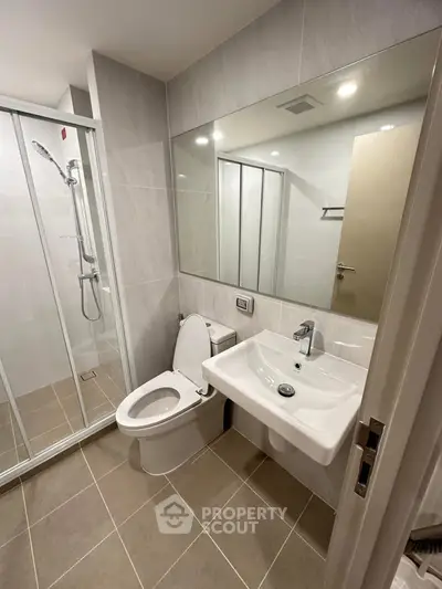 Modern bathroom with sleek fixtures and spacious shower in contemporary apartment.