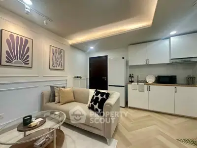 Modern living room with stylish decor and compact kitchen in open layout apartment.
