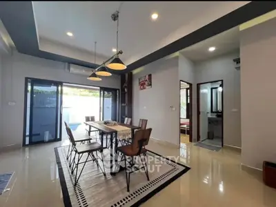 Spacious modern dining area with elegant lighting and large glass doors opening to a serene outdoor view.