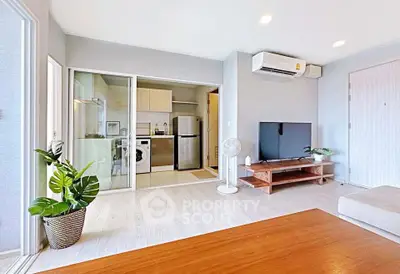 Modern living room with open kitchen, featuring sleek furniture and air conditioning.