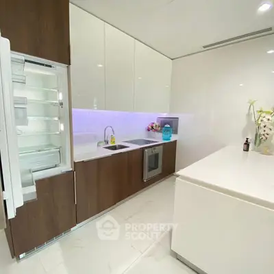 Modern kitchen with open fridge and sleek cabinetry in a stylish apartment