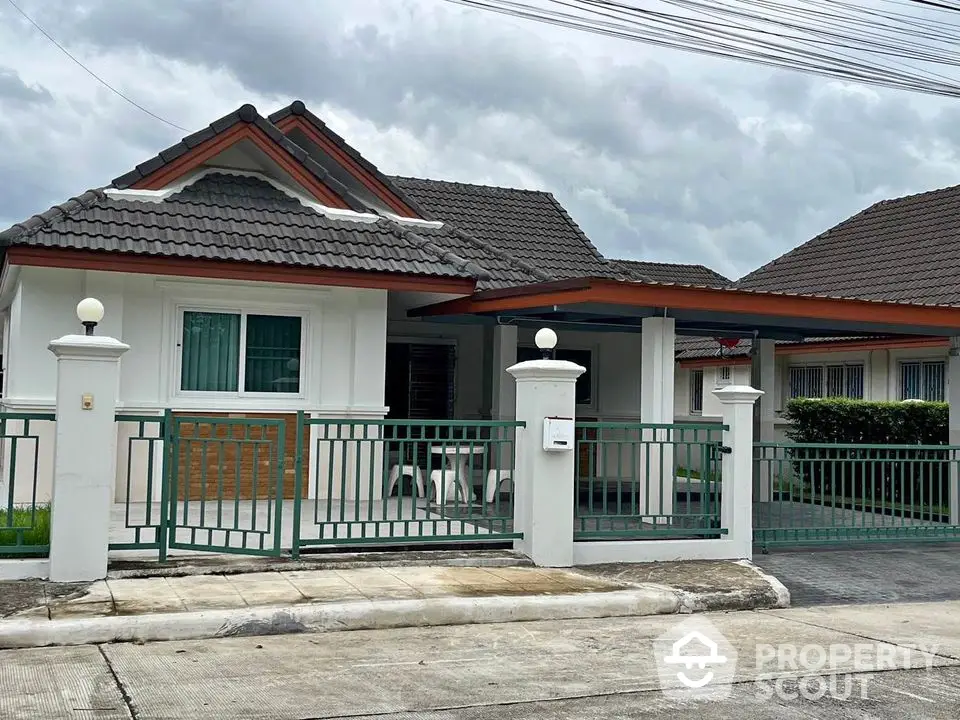 Charming single-story house with tiled roof and gated entrance in a serene neighborhood.