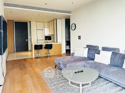 Modern living room with open kitchen, stylish furniture, and wooden flooring in a contemporary apartment.