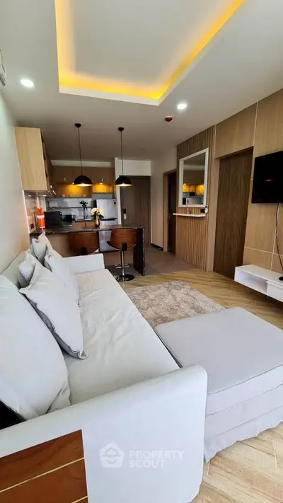 Modern living room with open kitchen, stylish lighting, and cozy seating area in a contemporary apartment.