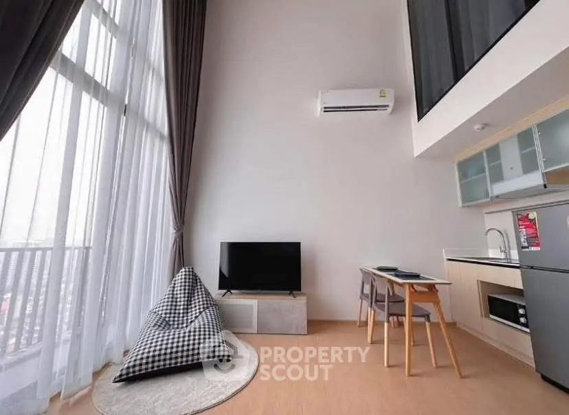 Modern loft apartment with high ceilings, large windows, and stylish kitchen area.