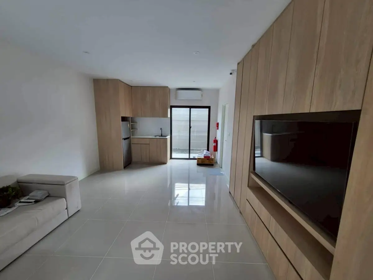 Modern open-plan living room with sleek kitchen and large TV unit