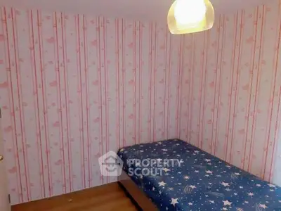 Cozy bedroom with charming floral wallpaper and a single bed with star-patterned bedding, ideal for a comfortable rest in a compact living space.