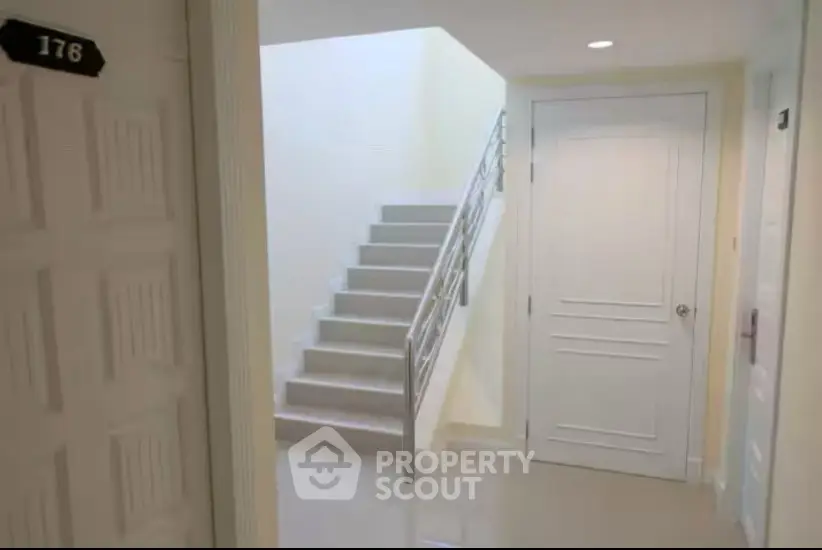 Modern apartment corridor with staircase and white doors
