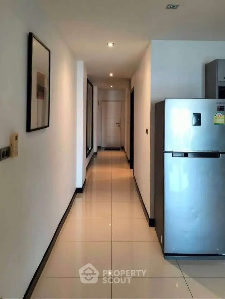 Modern apartment hallway with sleek refrigerator and polished tile flooring