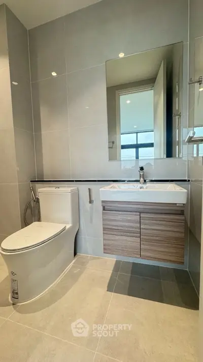 Modern bathroom with sleek fixtures and large mirror in a contemporary home.