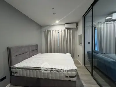 Modern bedroom with large bed and glass sliding doors in stylish apartment.