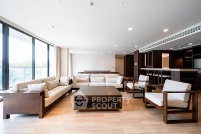 Spacious modern living room with elegant wooden furniture and large windows offering natural light.