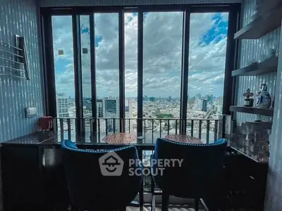 Stunning cityscape view from modern high-rise apartment balcony with seating area.