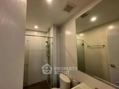 Modern bathroom with glass shower and sleek fixtures in contemporary apartment.