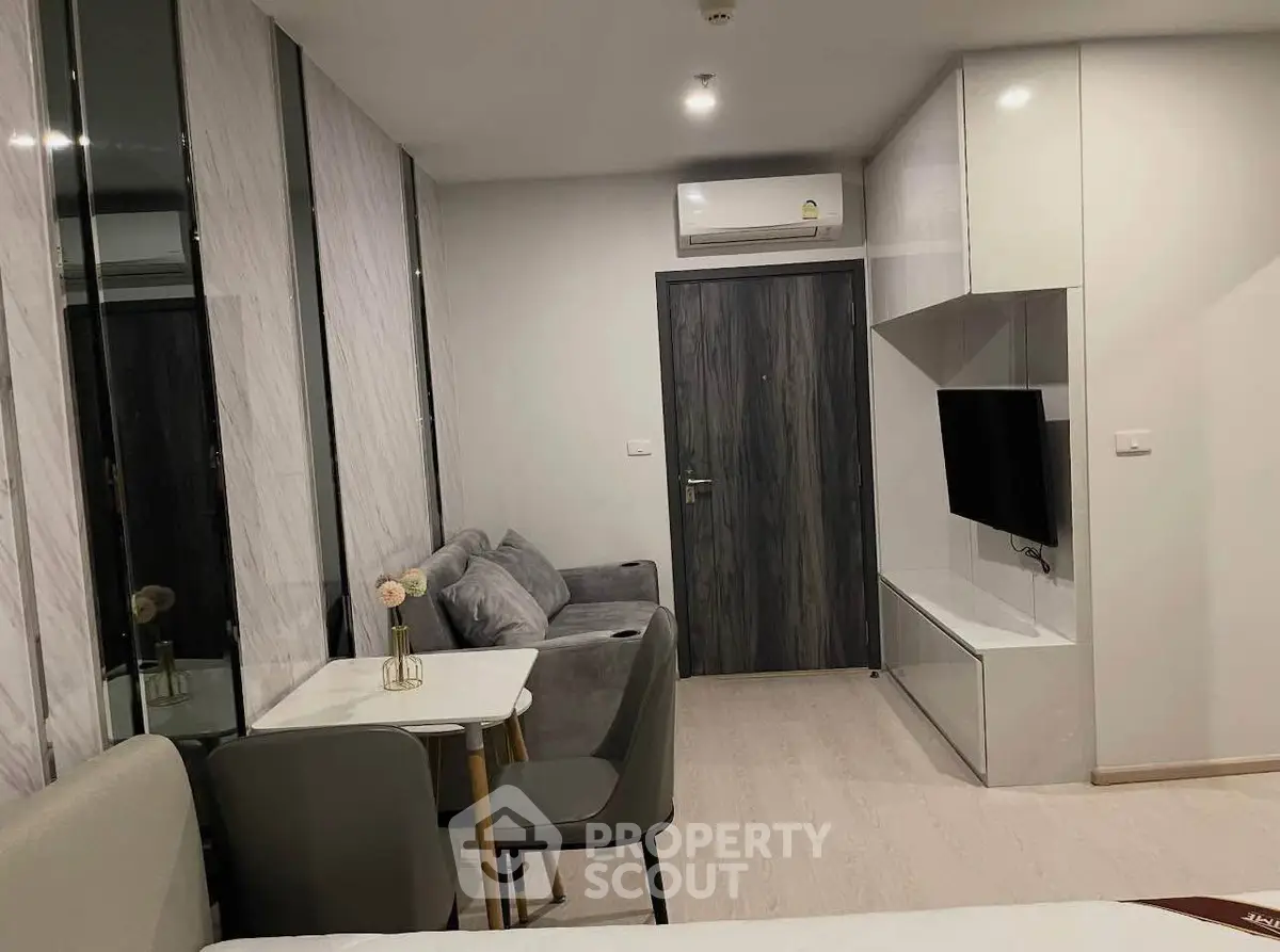 Modern living room with sleek furniture and wall-mounted TV in a stylish apartment.