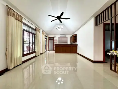 Spacious living room with elegant ceiling fan and large windows, perfect for natural light.