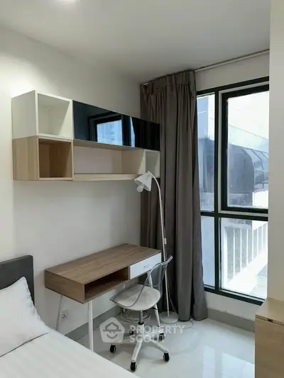 Modern bedroom with study area, featuring sleek desk, chair, and large window for natural light.