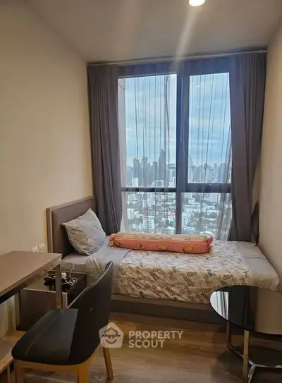 Cozy bedroom with city view, featuring a single bed and modern furnishings, perfect for urban living.