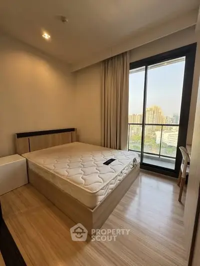 Modern bedroom with large window and city view, featuring a comfortable bed and wooden flooring.